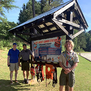 Eagle scout standing in front of his complete project, a life jacket station