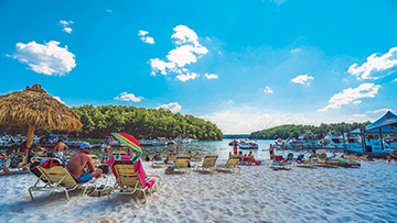 Beach setting - umbrellas, people sitting on the sand and in water