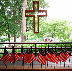 Hanging cross with American flags on table during a Memorial Day celebration