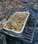 Grilling turkey and vegetables over campfire