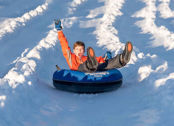 child tubing on snow covered hill