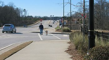 person walking dog in crosswalk along a Flowery Branch part of the Highland to Islands trail.