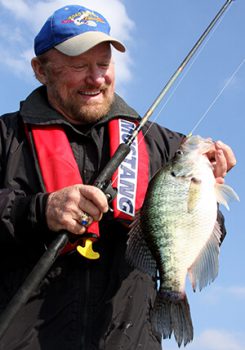 O'Neill Williams smiling, holding fishing pole with the fish he caught still on the line.