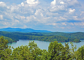 View of Carters Lake from a nearby mountain showing the mountains, lake, trees in foreground.