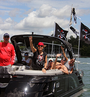 Speed boat with pirate flags and people waving.