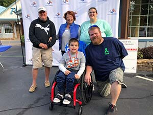 Group of four adults and one child in a wheelchair posing for photo