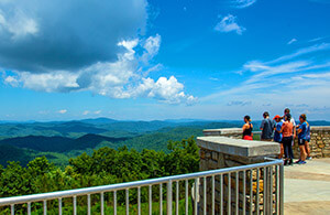 Visitors viewing the mountain view from top of Sassafrass Mountain - blue skies, white clouds, people standing near railing