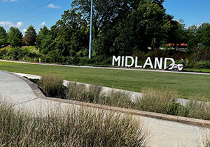 Midland sign - standing white letters with tractor beside it doing work.