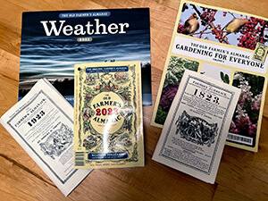 Farmer's Almanac and related magazines spread out on a wooden table. 