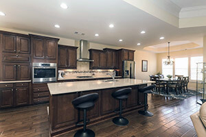 Example of "open" concept kitchen, dining, living room with brown cabinets, white counter tops, with seating, and wood floors.