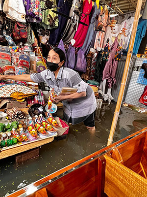 A souvenir selling merchant stands knee-deep in water in the flooded Floating Market.