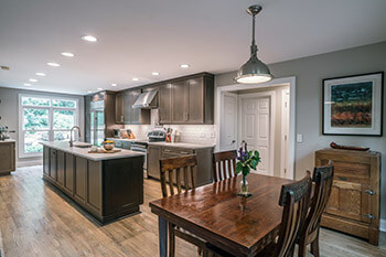 A newly remodeled kitchen showing can lights in ceiling and pendant light over kitchen table. 