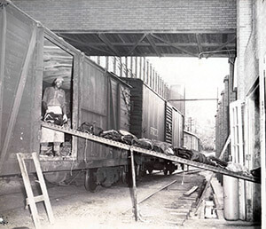Black and white photo of a Bona Allen worker unloading boxcars.