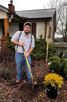Nursery owner and gardener Nathan Wilson outside in yard with shovel ready to dig hole for a new plant.