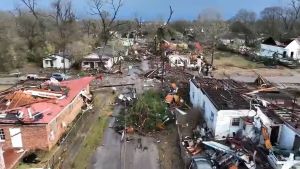 View of January tornado damage from EF 3 tornado in Alabama. Roofs missing, trees and debris block the road. 