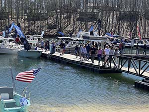 Lake Lanier Boat show attendees walking on the dock from shore to the boat slips to view boats up close and in the water.