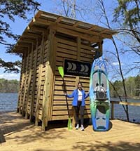 A Kayak Kiosk with kayak and paddler standing in front.