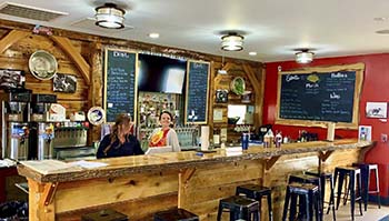 Inside the Spotted Pig - wood interior, workers at the counter and menu on the wall.