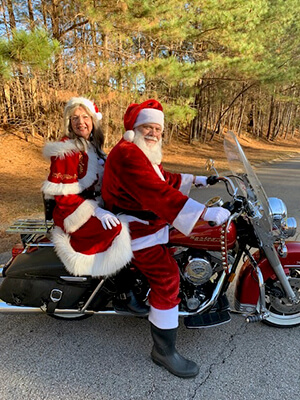 Bill and Terrilyn Donohue dressed as Santa and Mrs. Claus, riding on a motorcycle.