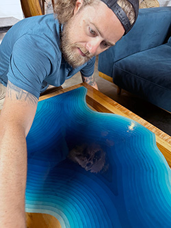 Wes Price, cleaning one of his wood pieces designed with epoxy inserted into the wood.