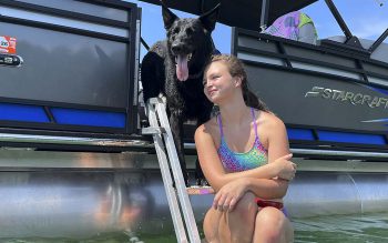Girl in swimsuit with black dog above her both sit on AquaStairs.