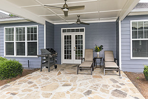 A covered outdoor porch with stone floor below and electric fan above.