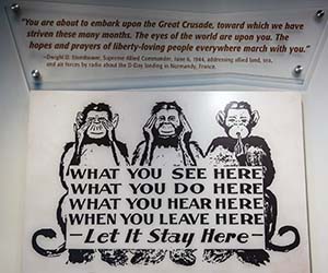 A sign with three monkeys reminding workers to not share information about their work with anyone. 