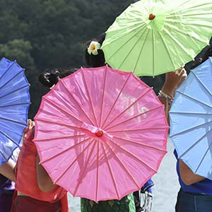 4 umbrellas, purple, pink, green and light blue are open during an opening ceremony performance.