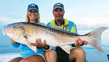 A man and a women both holding the same very large fish.