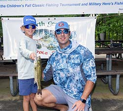 A young boy showing off the fish he caught.