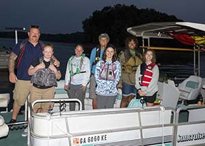 A group of male and female anglers standing on a pontoon boat, posing for photo during a fishing tournament.