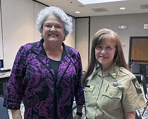 a head and shoulders photo of Terri Jondahl (left) purple shirt and Angie Johnson (right) in DNR uniform. 