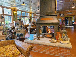 A view of the lobby area with a central fireplace that you can see through on four sides and gift shop items around. 