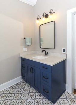 Photo of blue bathroom cabinets with white countertops. 