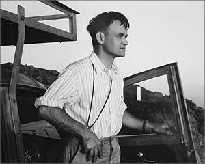 A copy of a black and white photo of photographer Pirkle Jones looking off into the distance and standing by a truck. Photo: by Ansel Adams. 