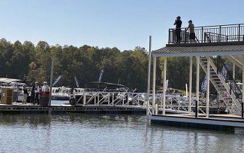A wide view of the docks at LandShark Landing at Lake Lanier Islands that shows people viewing boats in the water. On the right there is a two-story dock with people standing on the top deck.