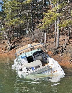 A view of a partially submerged, abandoned motorboat near the shoreline of Lake Lanier.