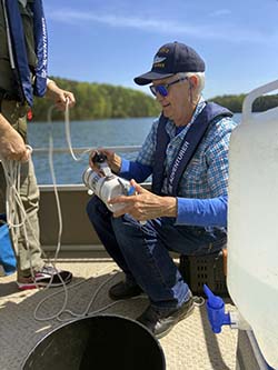 A CRK volunteer sits on a boat on Lake Lanier with a device in his hand for measuring water quality. 