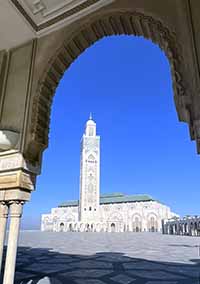 View of the Hassan II Mosque taken through an archway with blue sky in background.