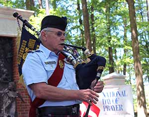 A head and shoulder view of Pipe Major ML Loudermilk as he plays the bagpipes.