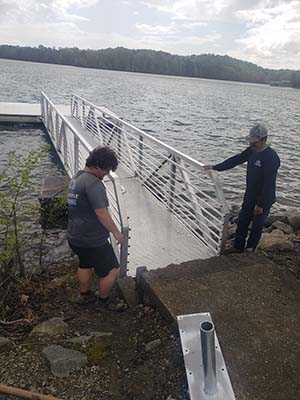 Two Southeastern Dock Supply employees stand on either side of the new dock they are installing at Six Mile boat ramp.